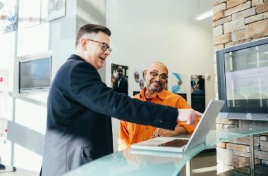 Two businessmen having a lively discussion in a modern office setting, pointing at a laptop screen.